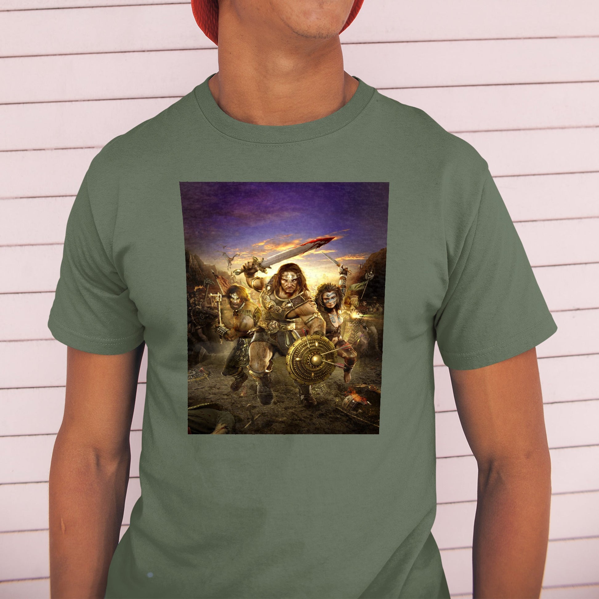 Age of Conan Hyborian Adventures tee worn by a model in a cap, green
