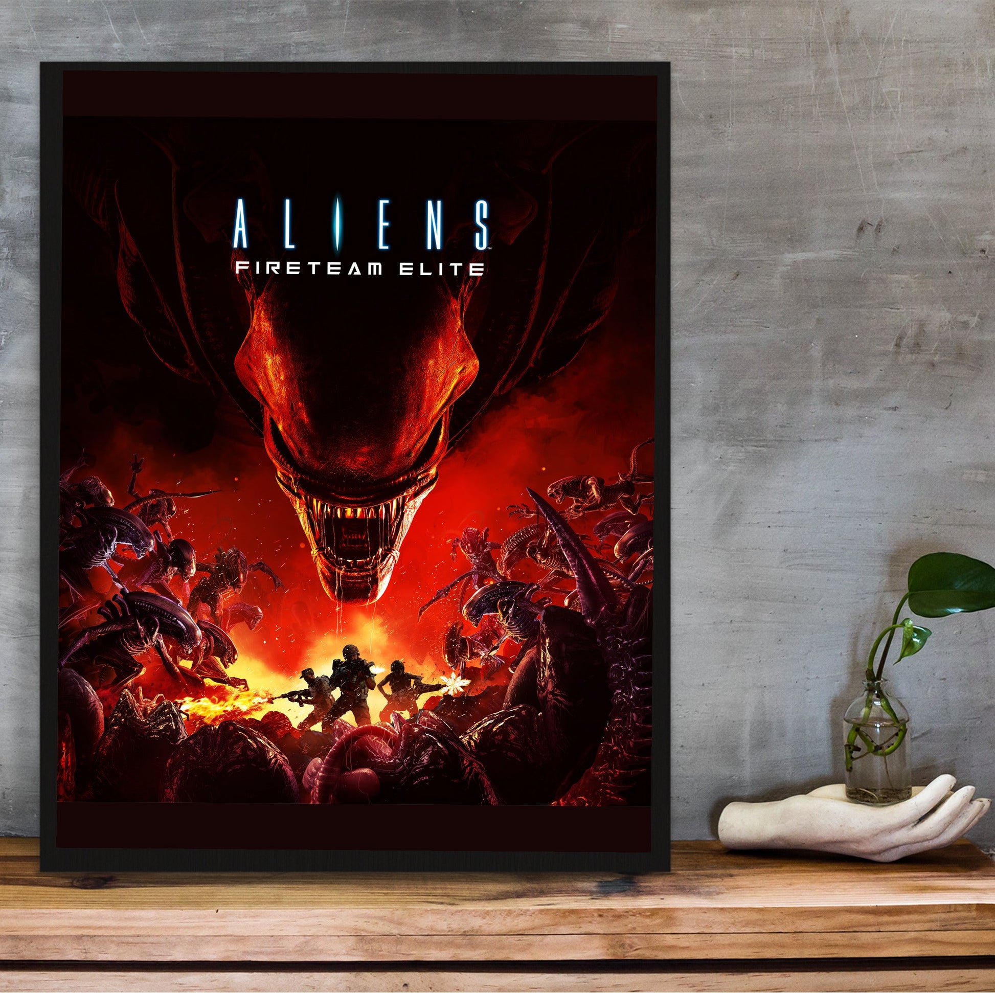 Aliens Fireteam Elite cover art in a black frame on a wooden shelf against concrete