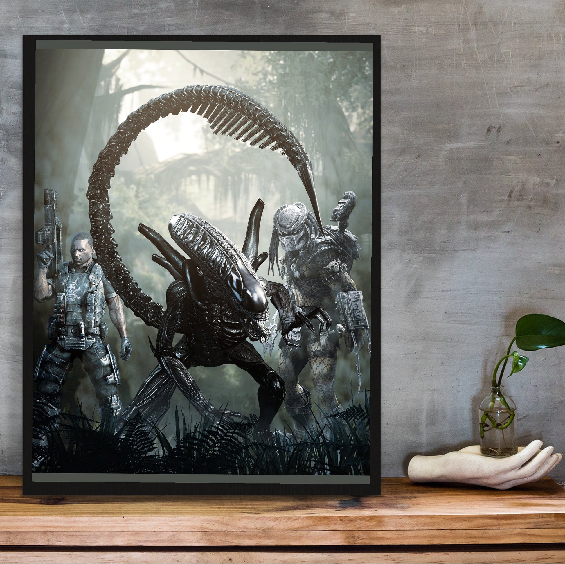 Aliens vs. Predator 2010 alien promo art in a black frame on a wooden shelf against concrete