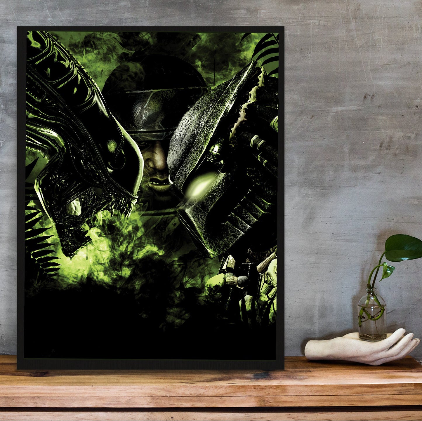 Aliens vs. Predator 2010 promotional art in a black frame on a wooden shelf against concrete
