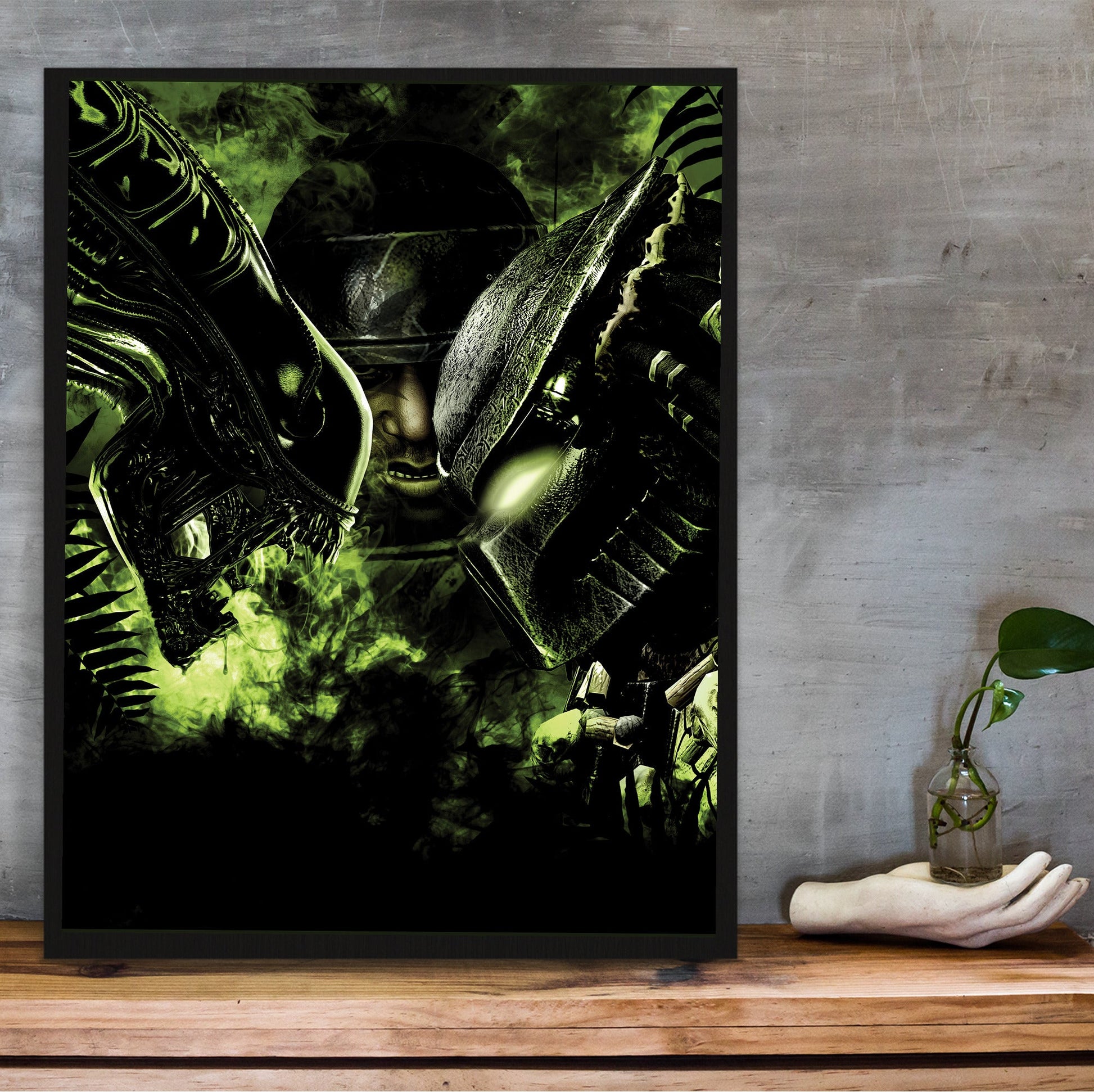 Aliens vs. Predator 2010 promotional art in a black frame on a wooden shelf against concrete