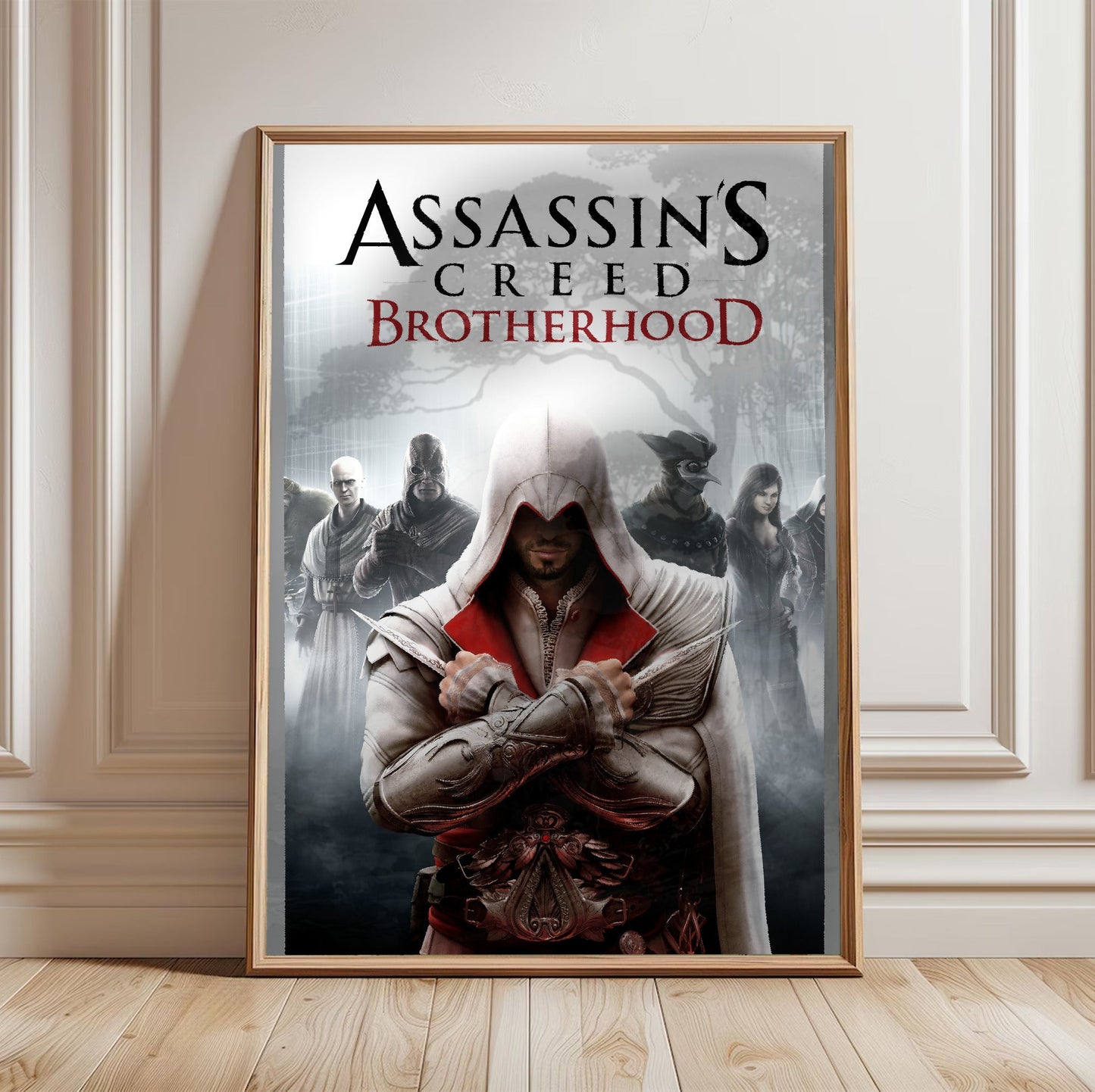 Assassin's Creed Brotherhood cover art in a light oak frame leaning against a white wall