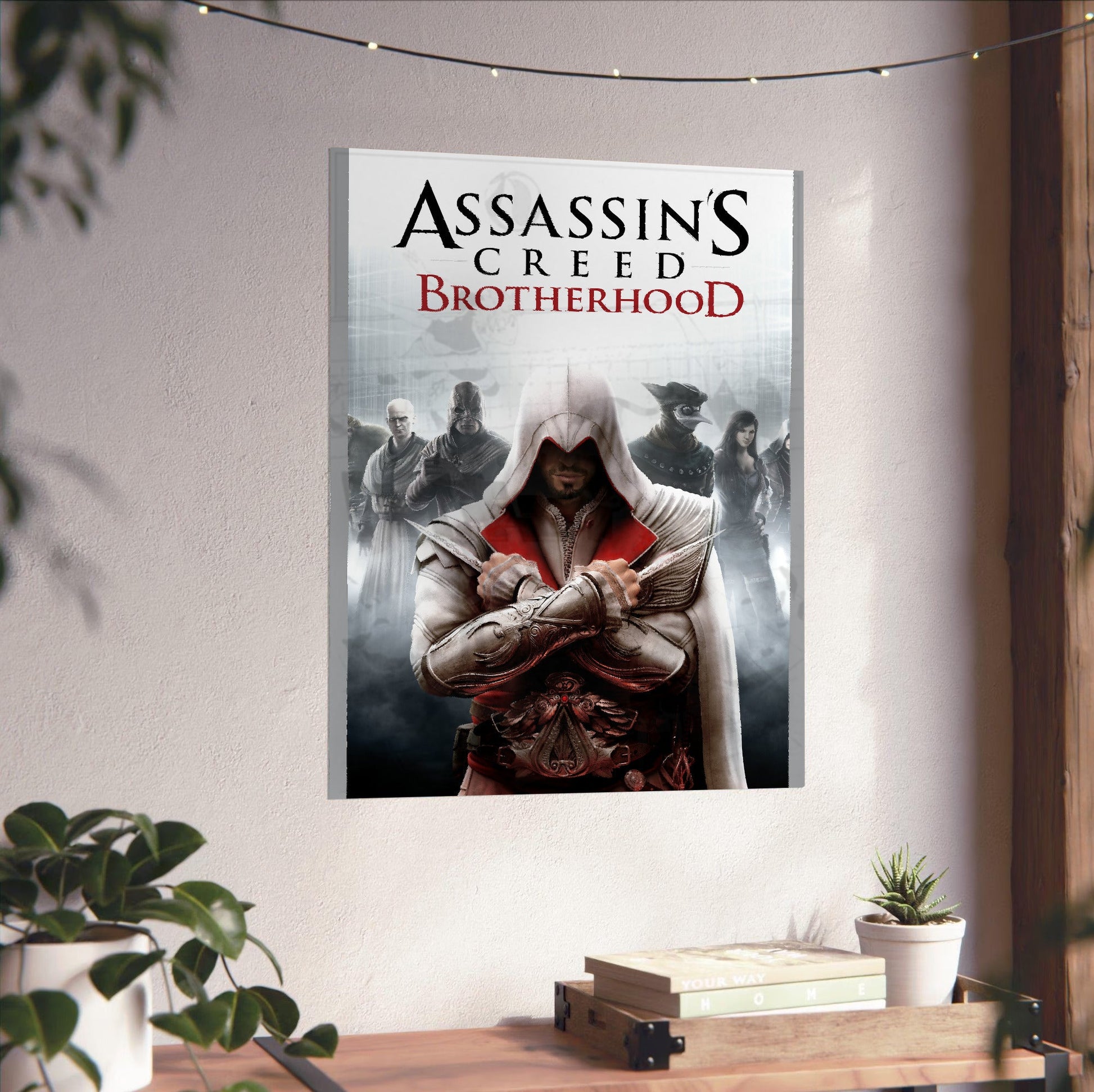 Assassin's Creed Brotherhood cover art unframed on a white wall above a desk