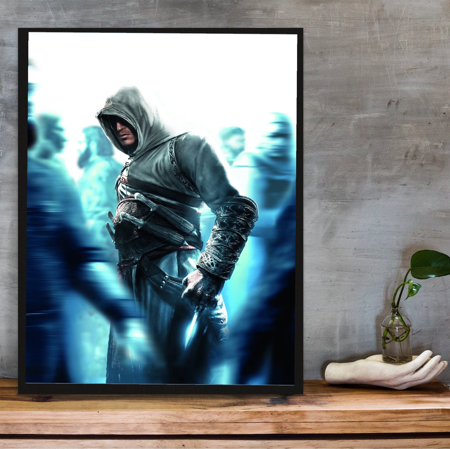 Assassin's Creed crowd key art in a black frame on a wooden shelf against concrete