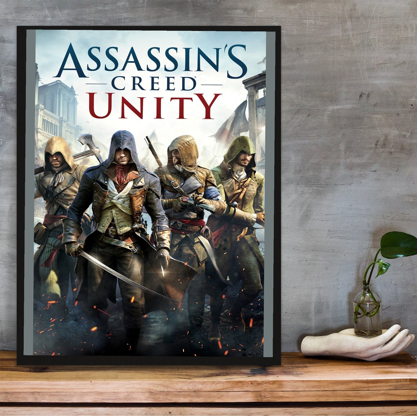 Assassin's Creed Unity cover art in a black frame on a wooden shelf against concrete