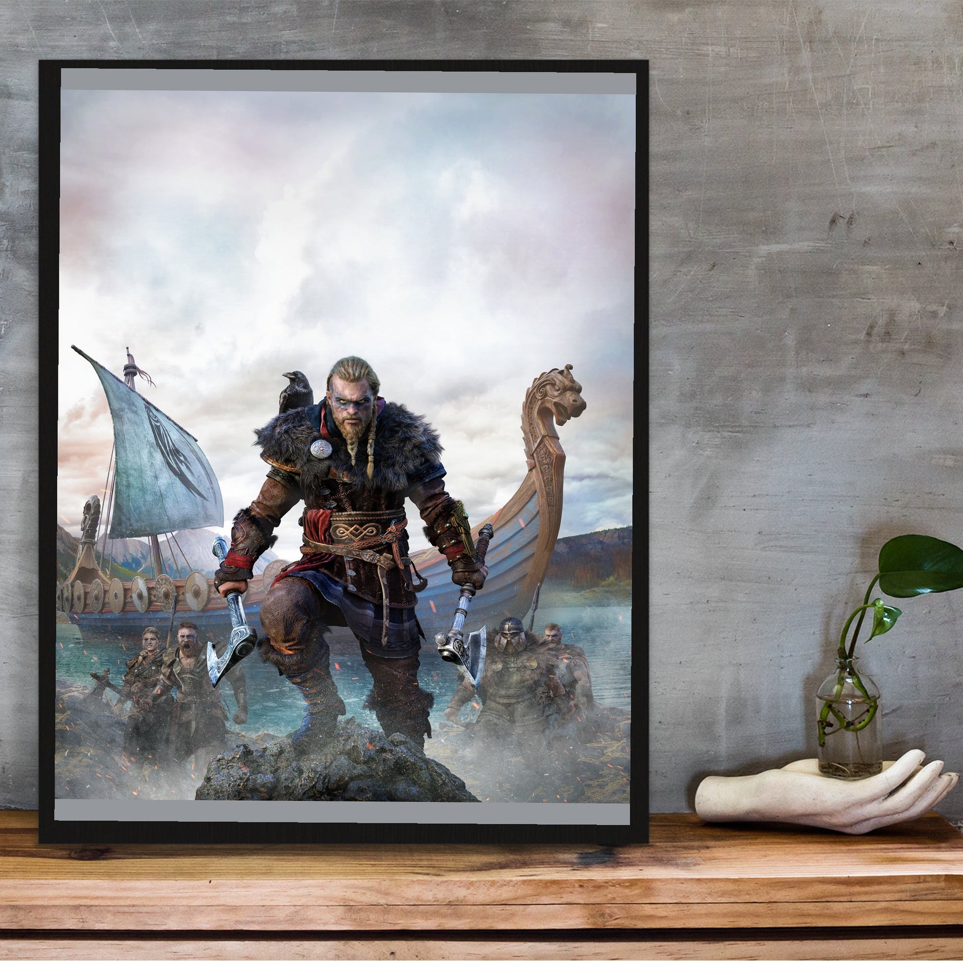Assassin's Creed Valhalla cover art in a black frame on a wooden shelf against concrete