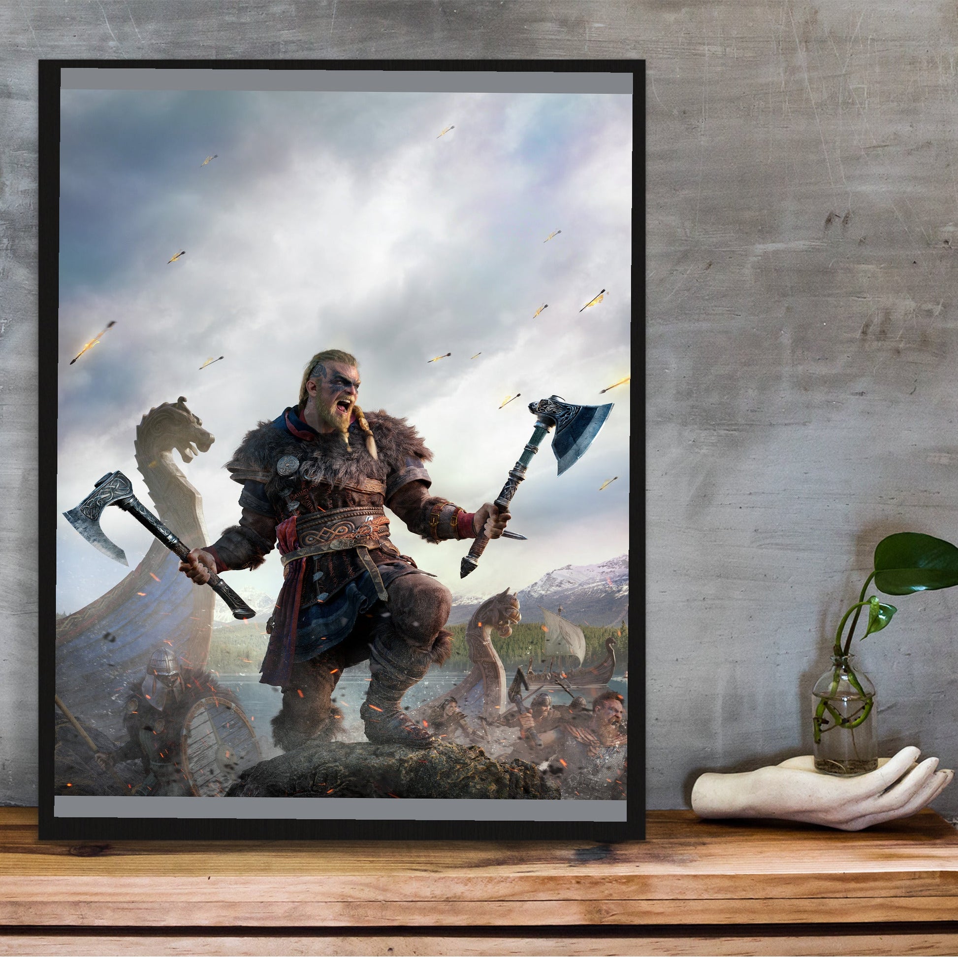 Assassin's Creed Valhalla key art in a black frame on a wooden shelf against concrete
