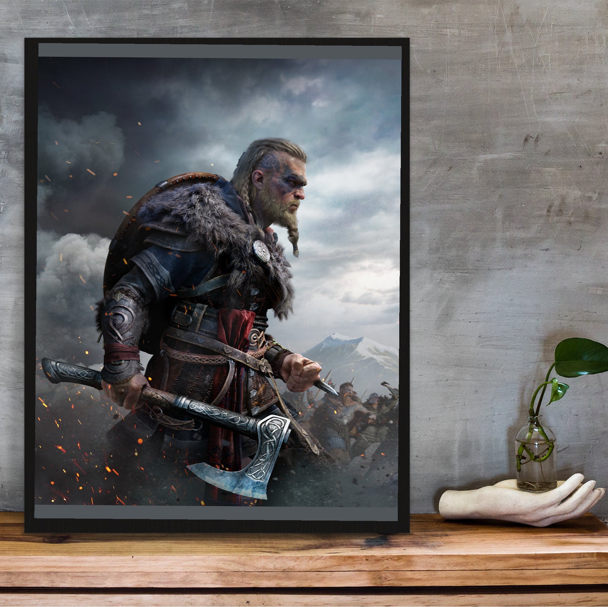 Assassin's Creed Valhalla Ultimate Edition key art in a black frame on a wooden shelf against concrete