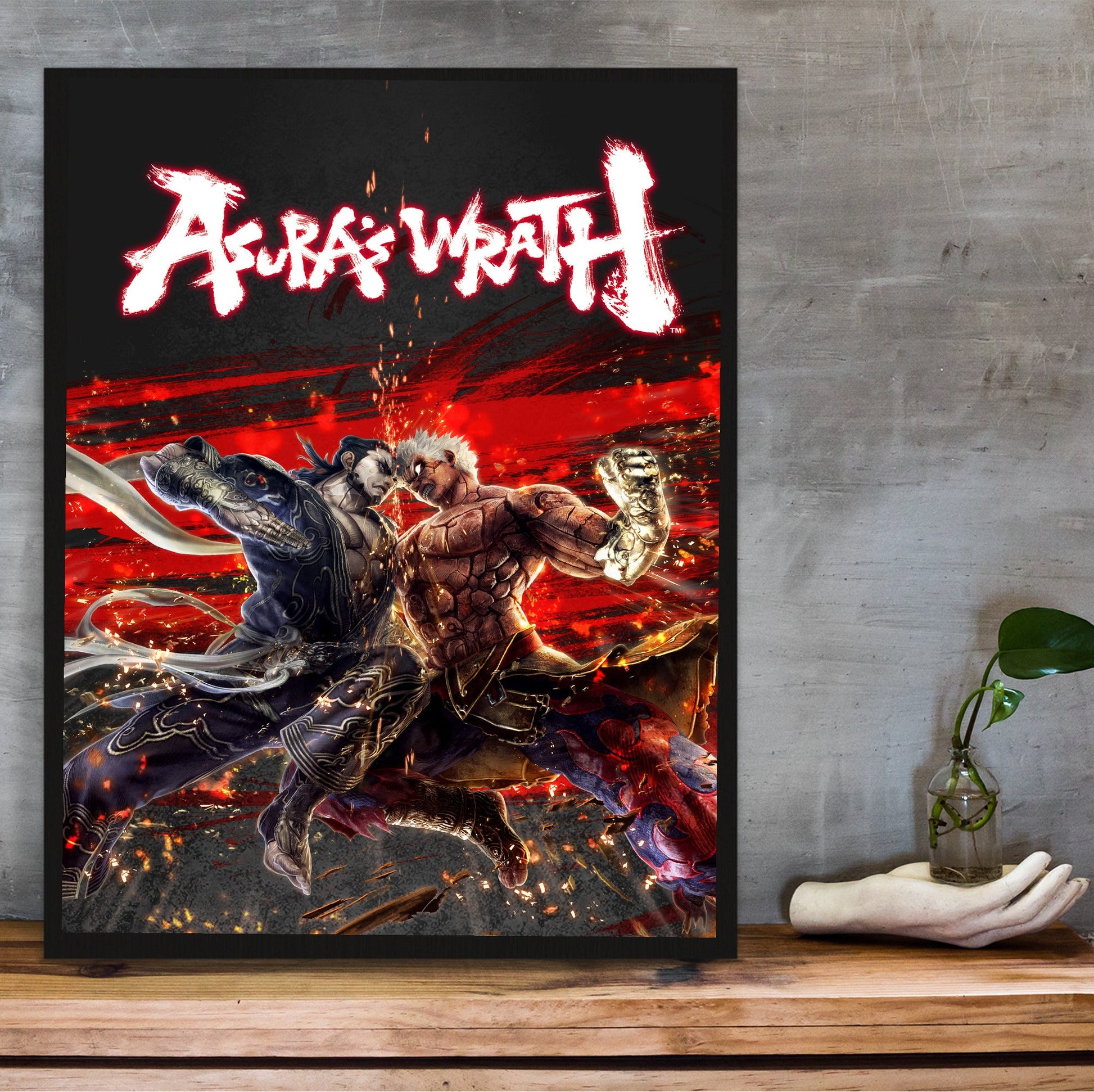 Asura's Wrath Yasha vs Asura art in a black frame on a wooden shelf against concrete