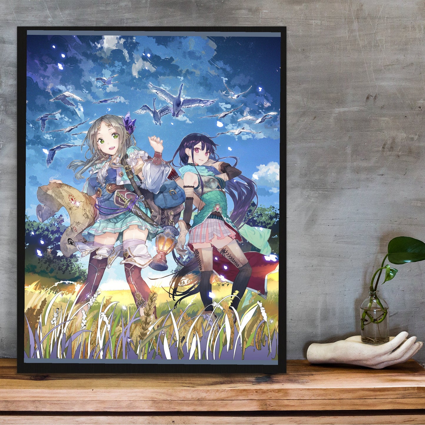 Atelier Firis The Alchemist and the Mysterious Journey Official Key Art in a black frame on a wooden shelf against concrete