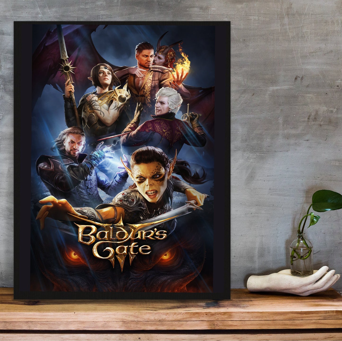 Baldurs Gate 3 Official Key Art in a black frame on a wooden shelf against concrete
