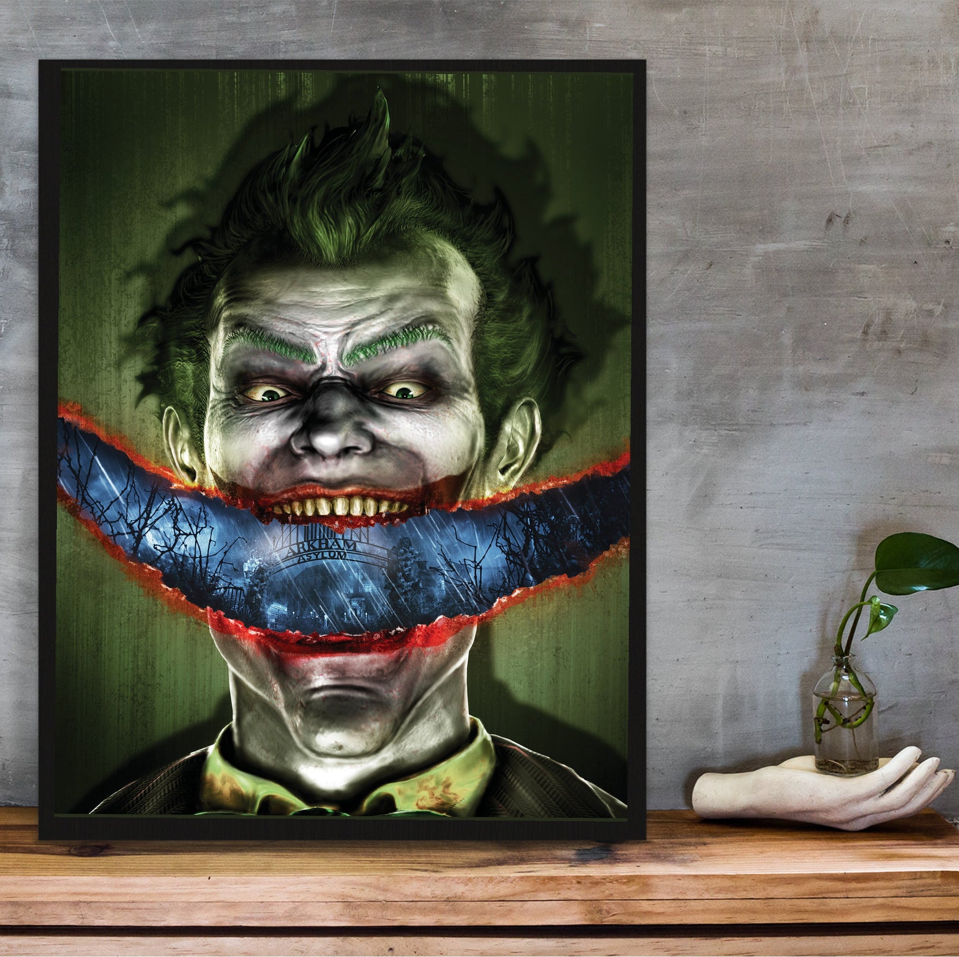 Batman Arkham Asylum Joker stitched smile art poster in a black frame on a wooden shelf against concrete
