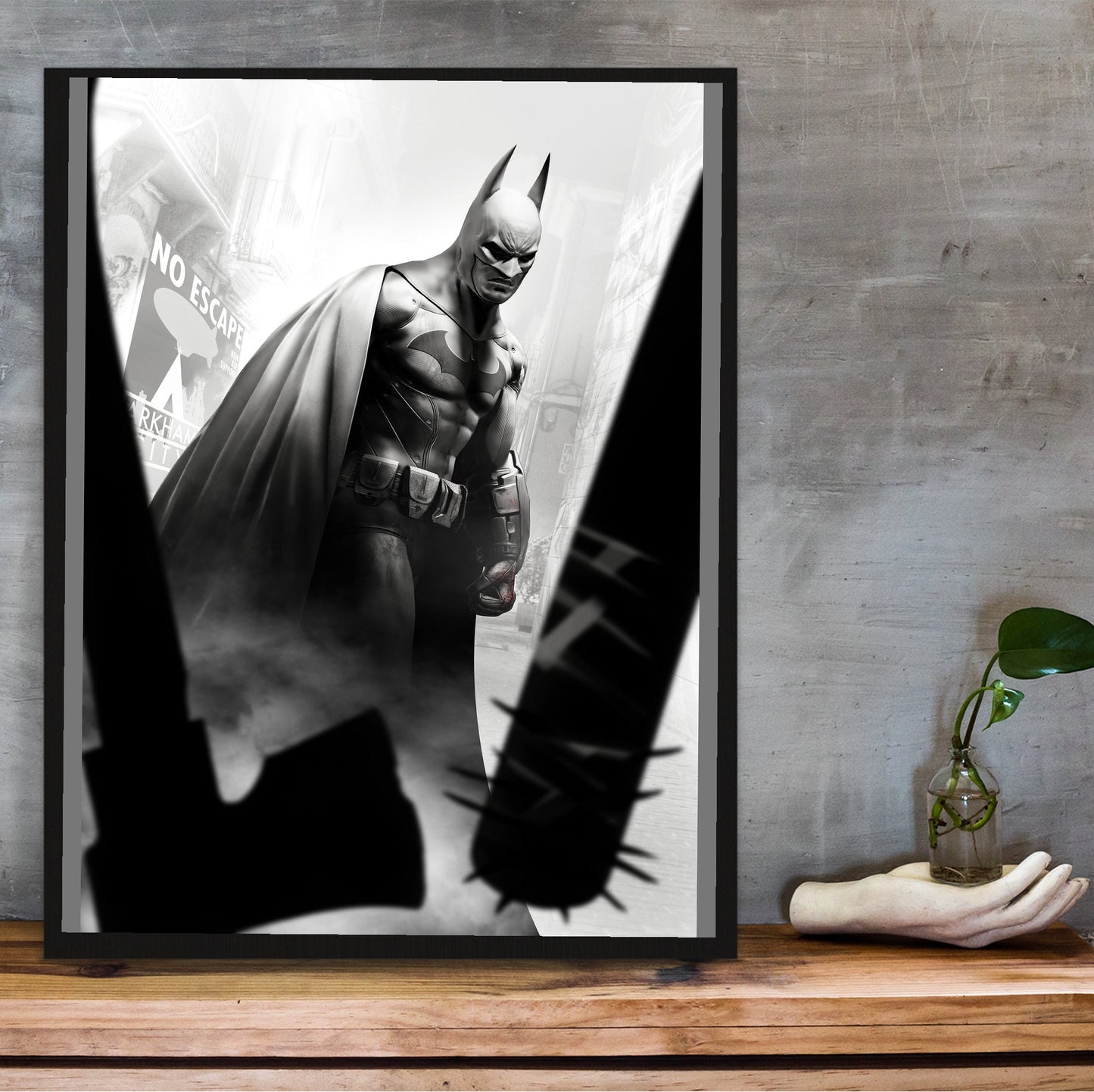 Batman Arkham City Batman vs thugs art poster in a black frame on a wooden shelf against concrete