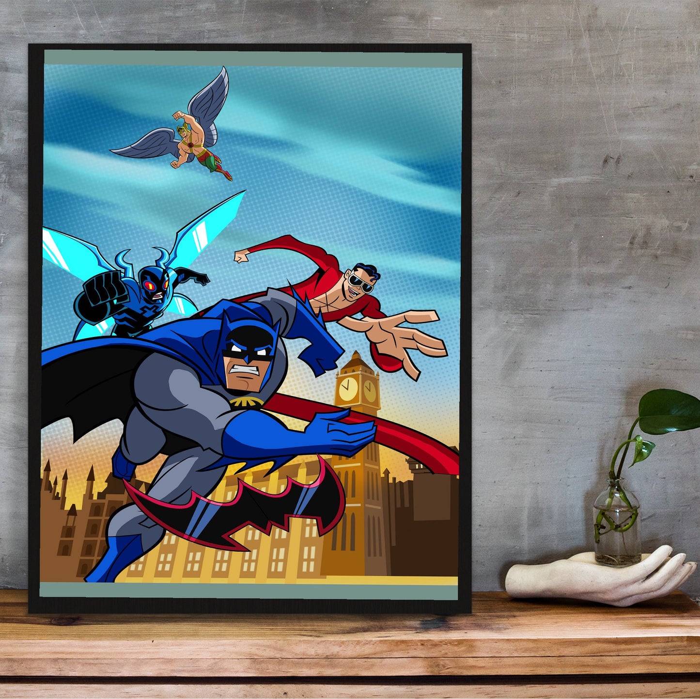 Batman The Brave and the Bold videogame cover art poster in a black frame on a wooden shelf against concrete