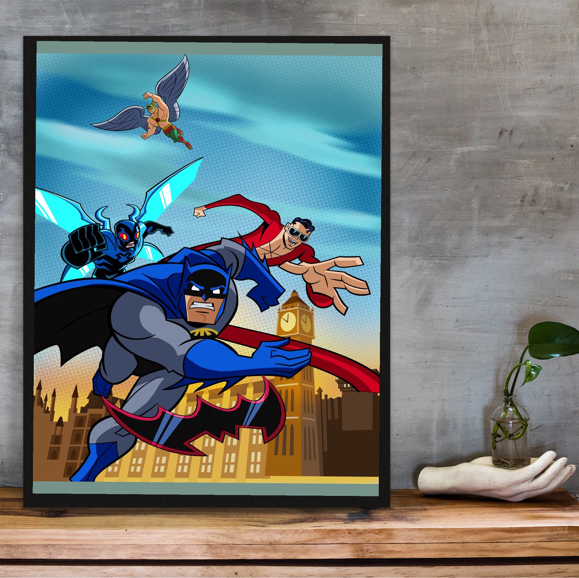 Batman The Brave and the Bold videogame cover art poster in a black frame on a wooden shelf against concrete