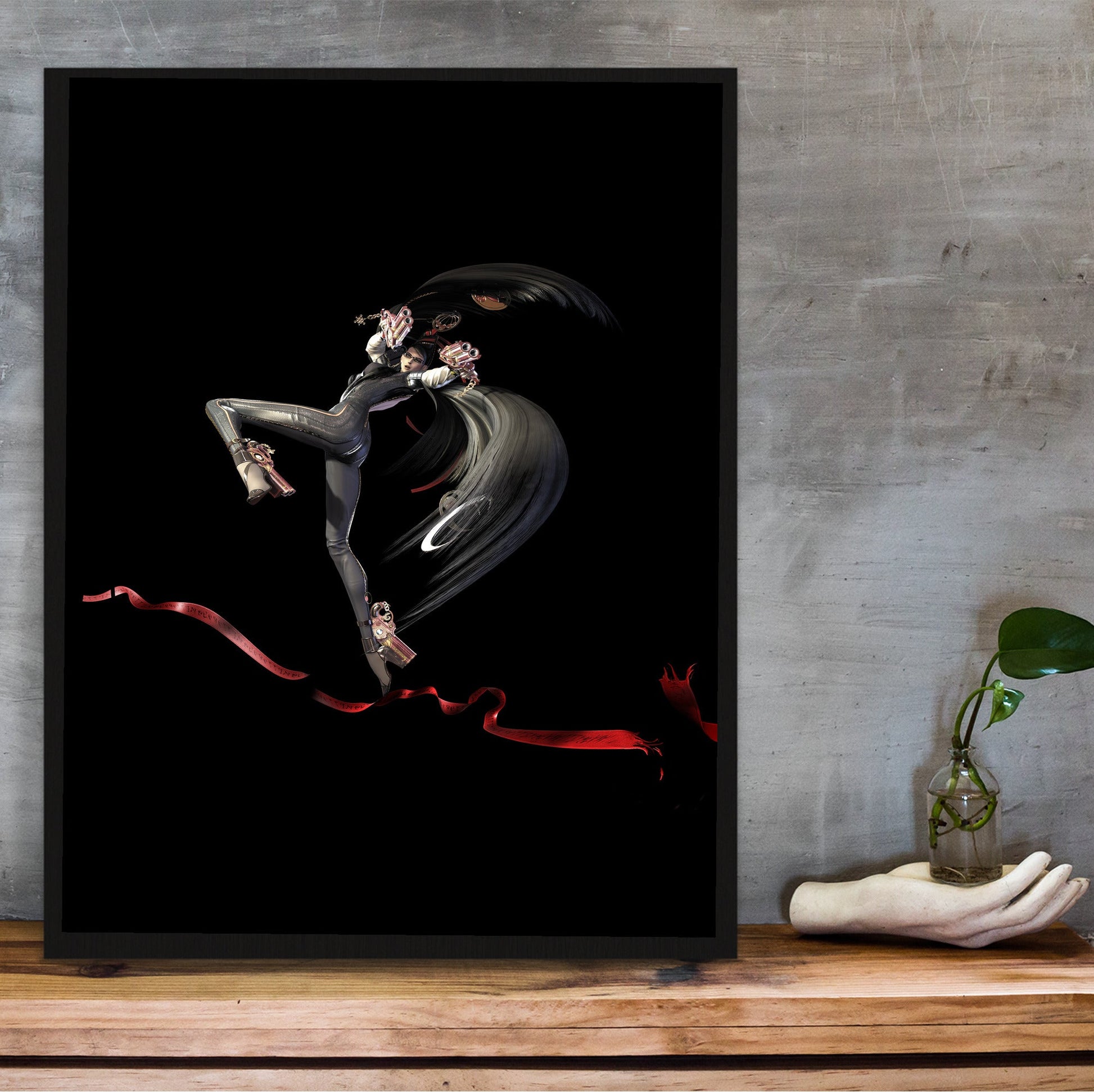 Bayonetta action pose art poster in a black frame on a wooden shelf against concrete