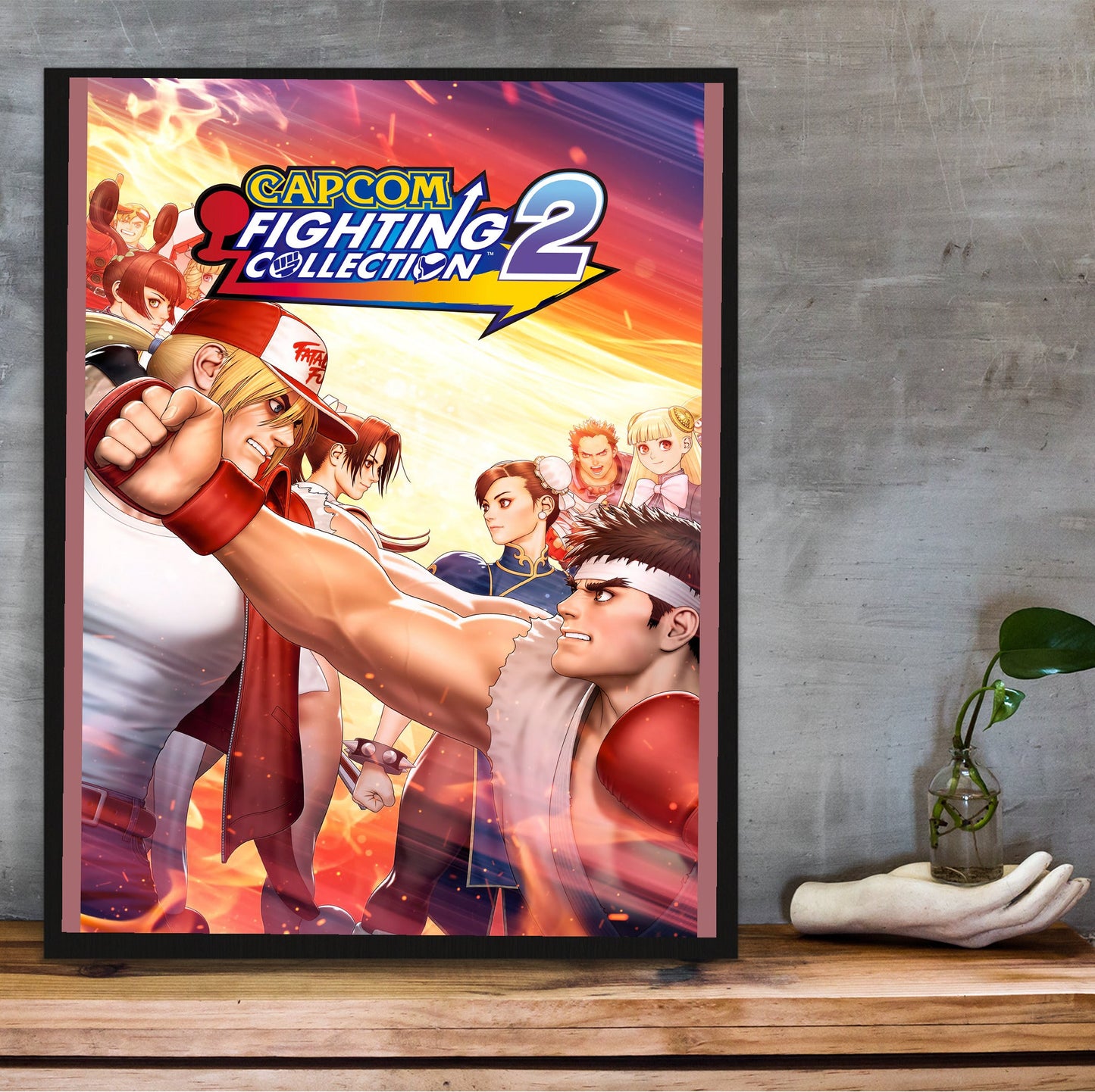 Capcom Fighting Collection 2 key art with logo in a black frame on a wooden shelf against concrete