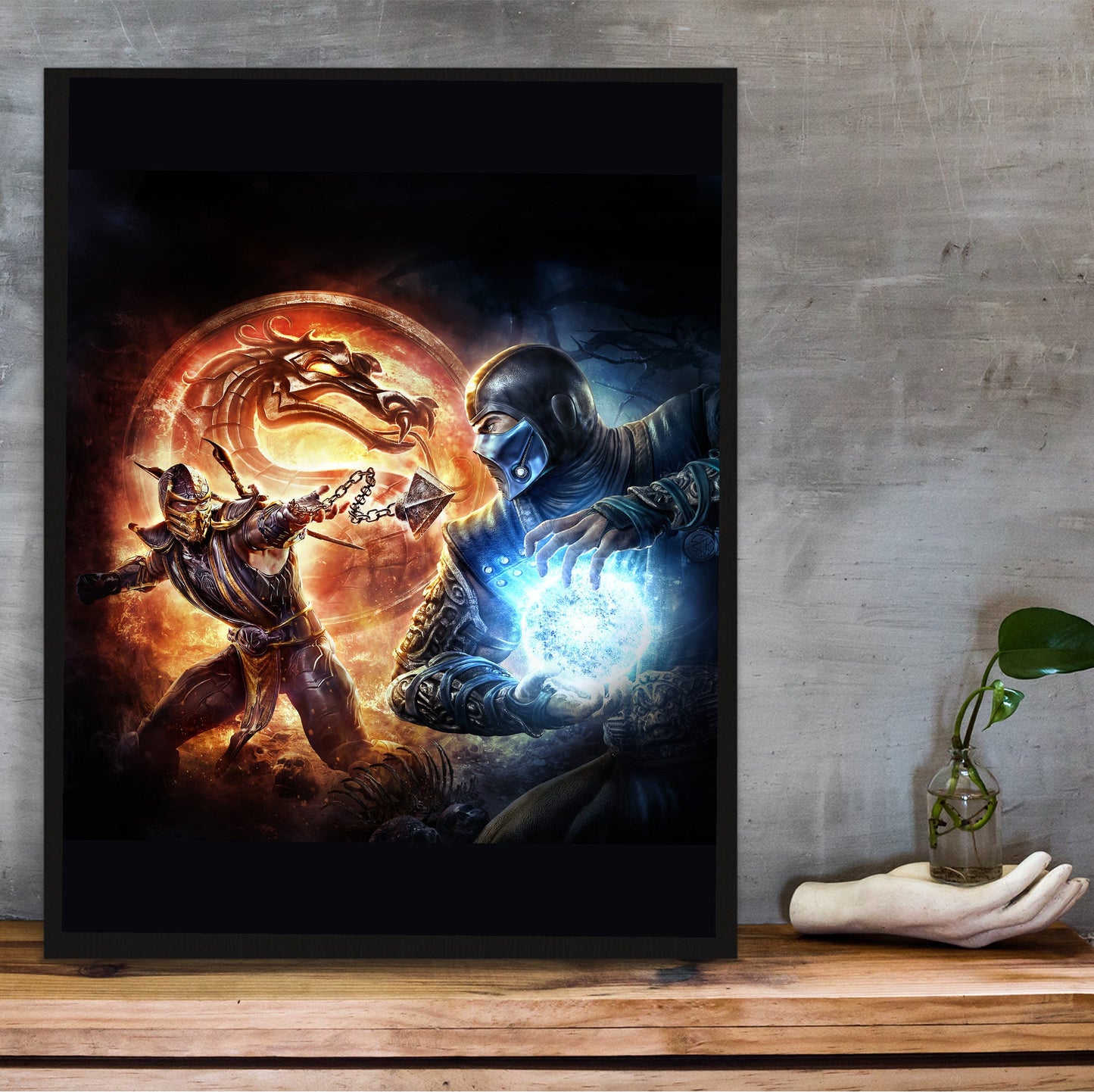 Mortal Kombat 9 Scorpion vs Sub-Zero cover art in a black frame on a wooden shelf against concrete