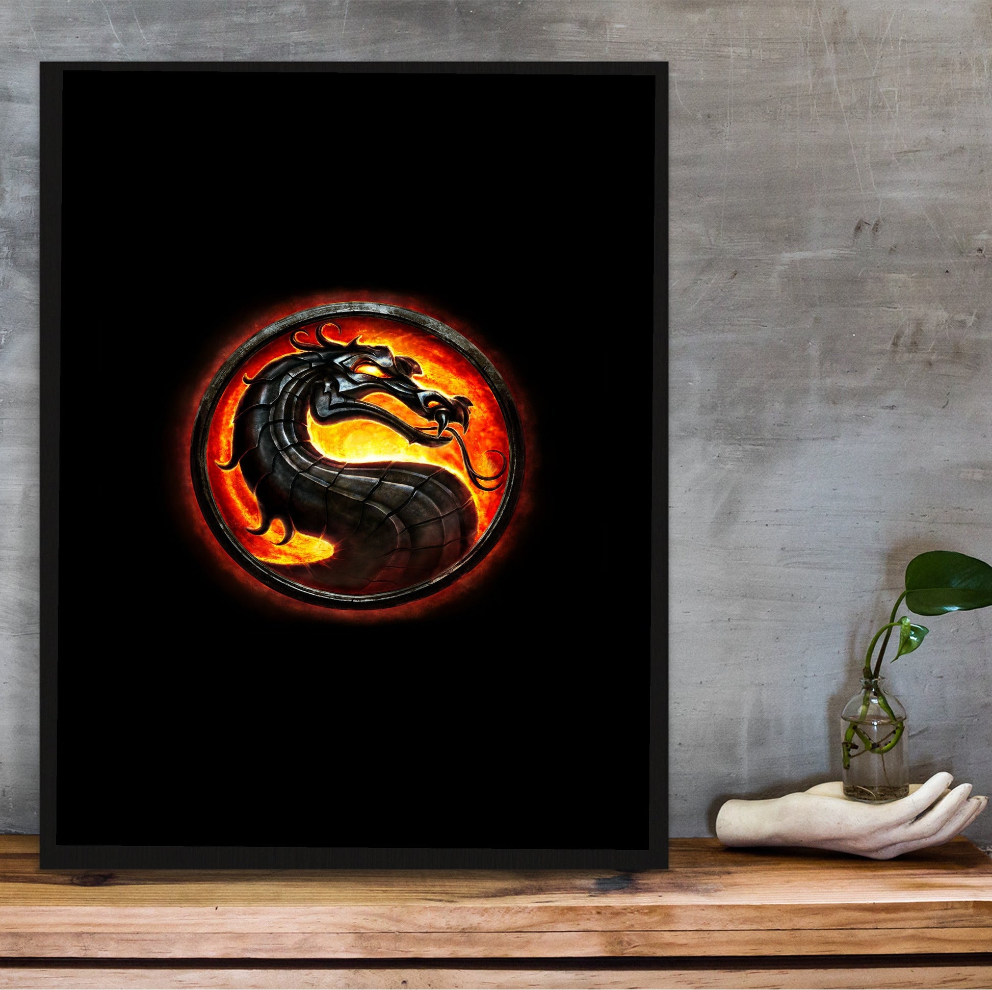 Mortal Kombat dragon emblem in a black frame on a wooden shelf against concrete