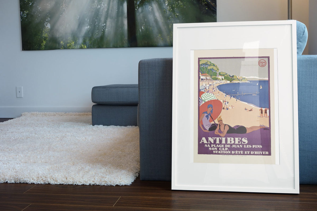 Antibes Juan les Pins poster leaning beside a blue sofa