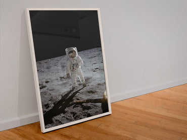 Apollo 11 Buzz Aldrin moonwalk poster in a white frame leaning against a wall