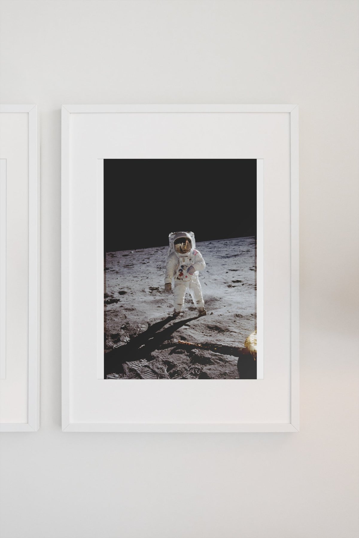 Apollo 11 Buzz Aldrin moonwalk poster in a white frame on a light wall