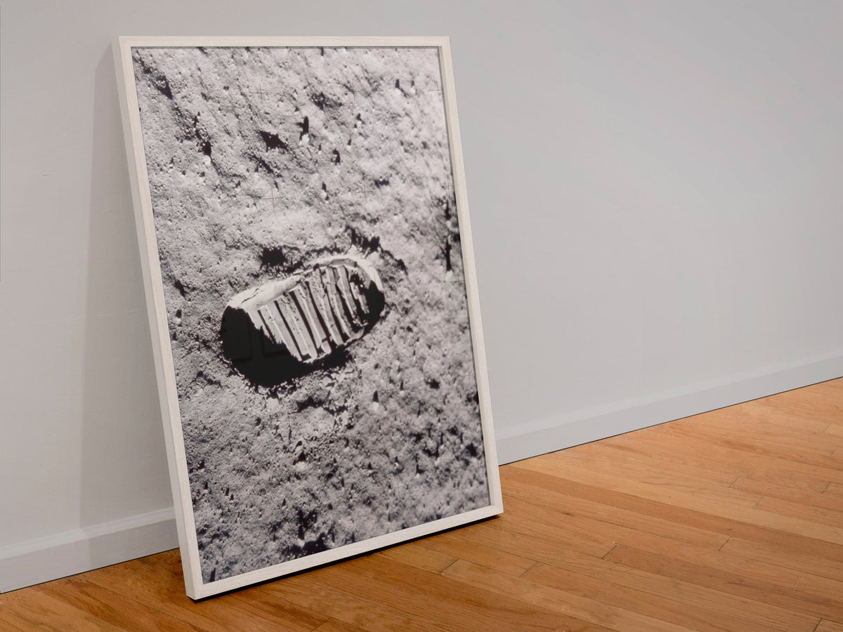 Apollo 11 bootprint on the Moon poster in a white frame leaning against a wall