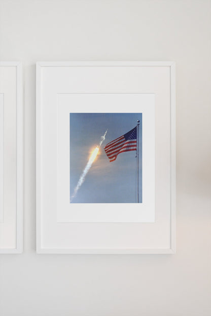 Apollo 11 rocket launch with the US flag poster in a white frame on a light wall