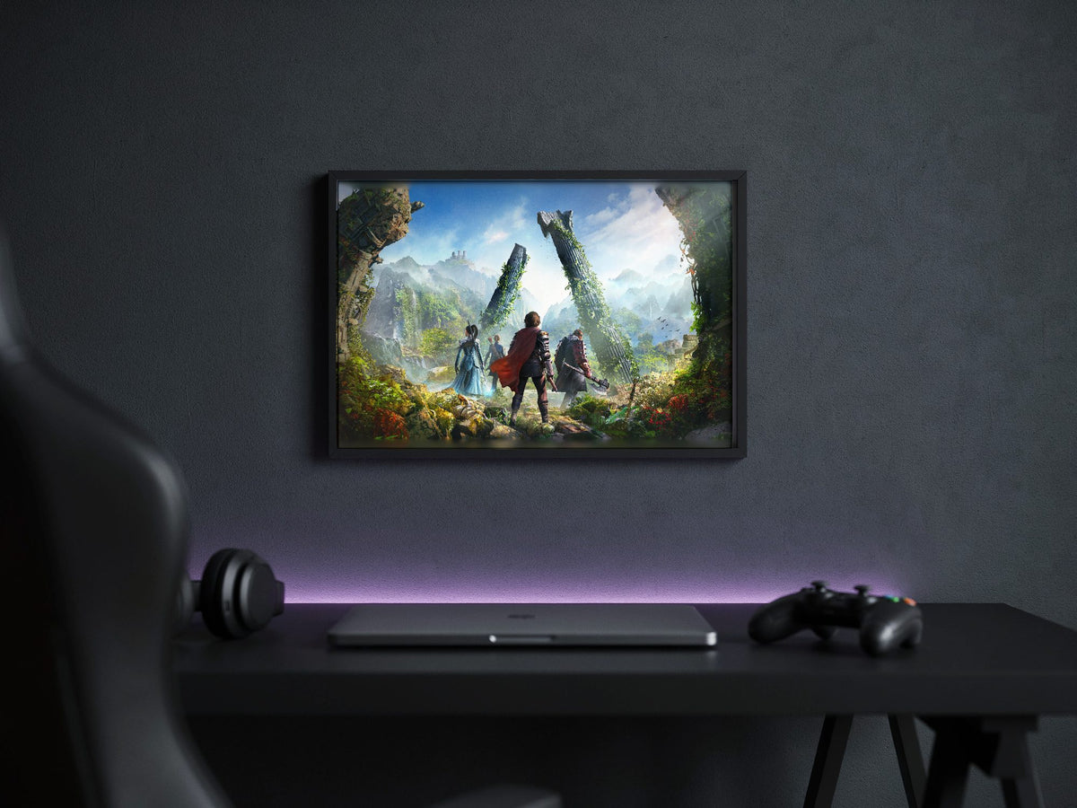 ArcheAge Chronicles Key Art poster in a black frame above a gaming desk