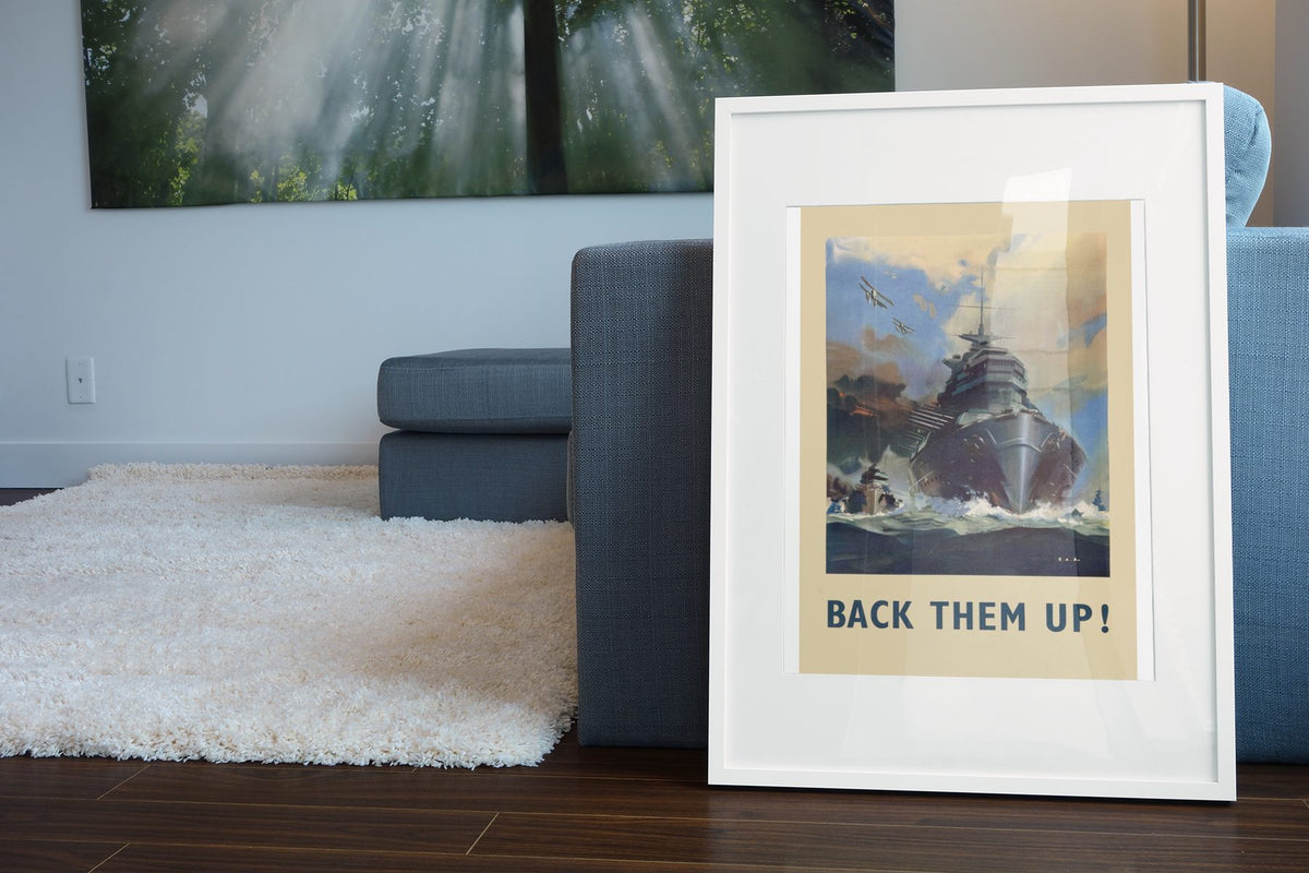 Back Them Up Battleship poster leaning beside a blue sofa
