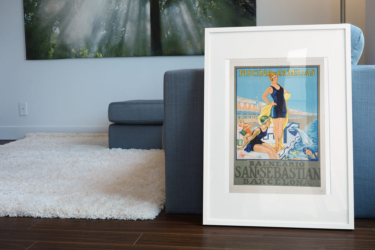 Balneario San Sebastian Barcelona poster leaning beside a blue sofa