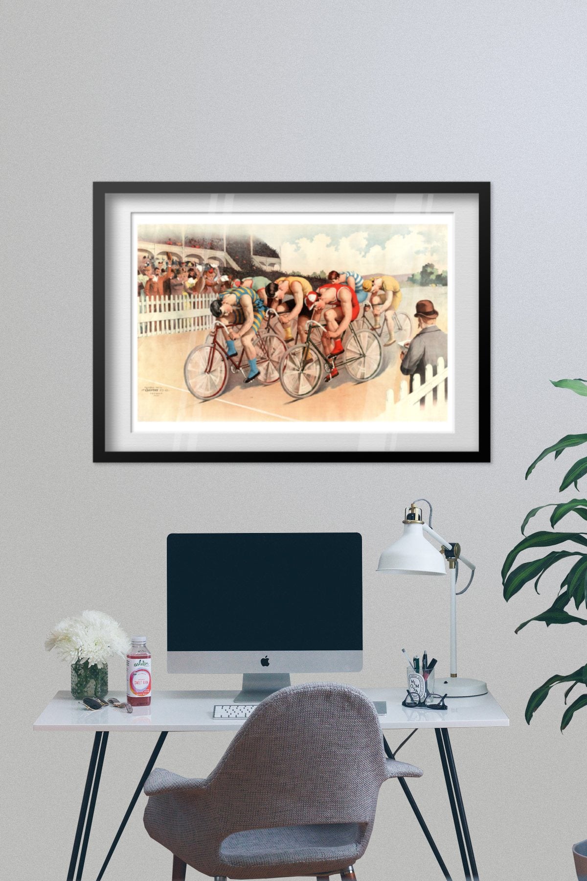 Bicycle Race poster framed on a grey wall above a desk