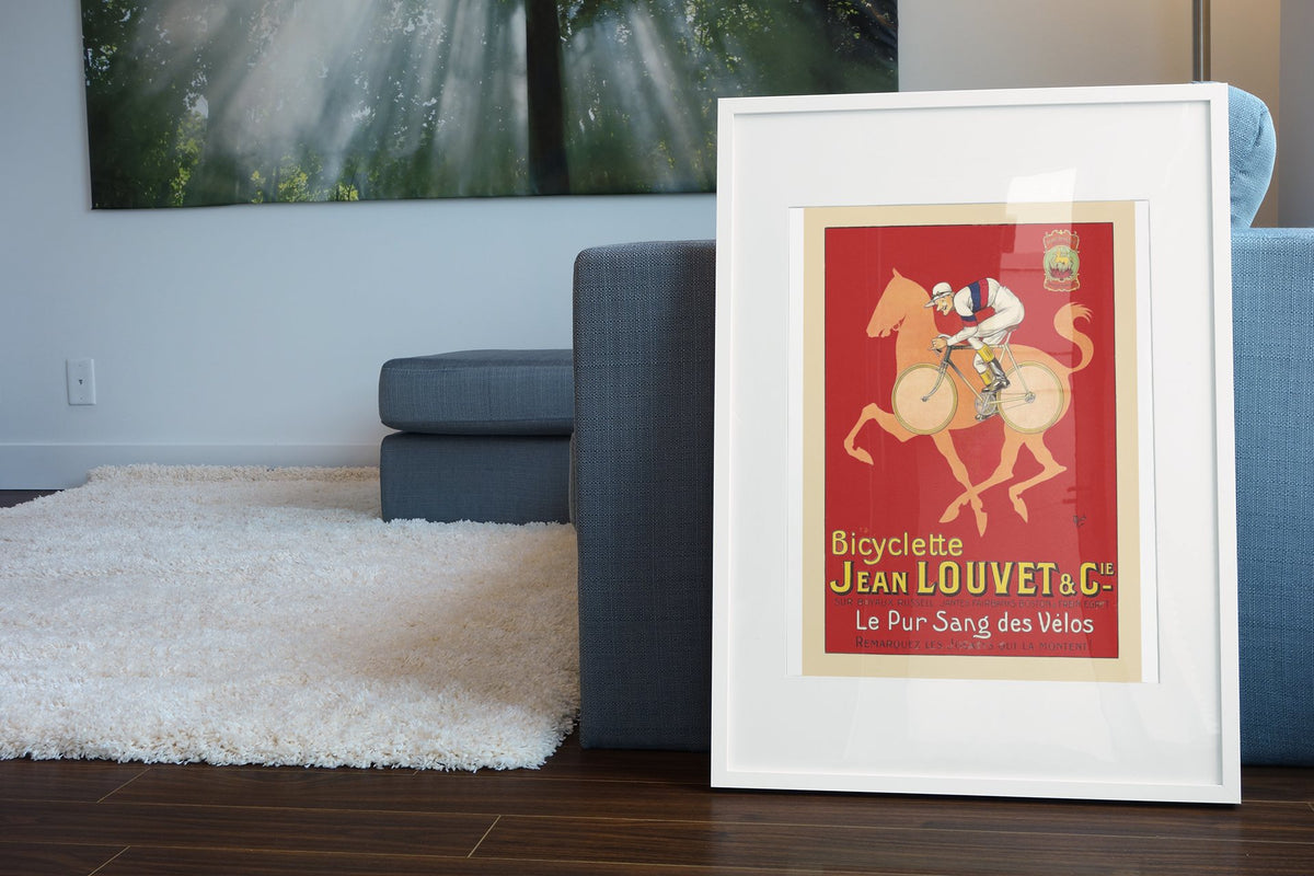 Jean Louvet Pur Sang des Velos poster leaning beside a blue sofa
