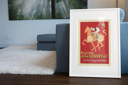 Jean Louvet Pur Sang des Velos poster leaning beside a blue sofa