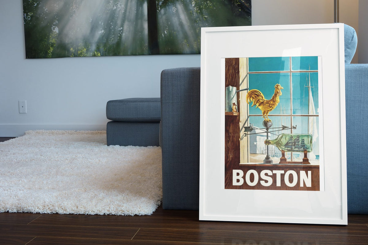 Boston Fly TWA poster leaning beside a blue sofa