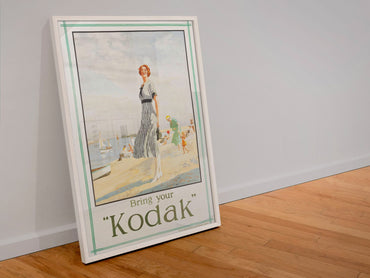 Bring Your Kodak 1925 poster in a white frame leaning against a wall