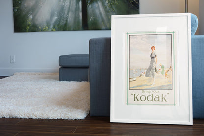 Bring Your Kodak 1925 poster leaning beside a blue sofa