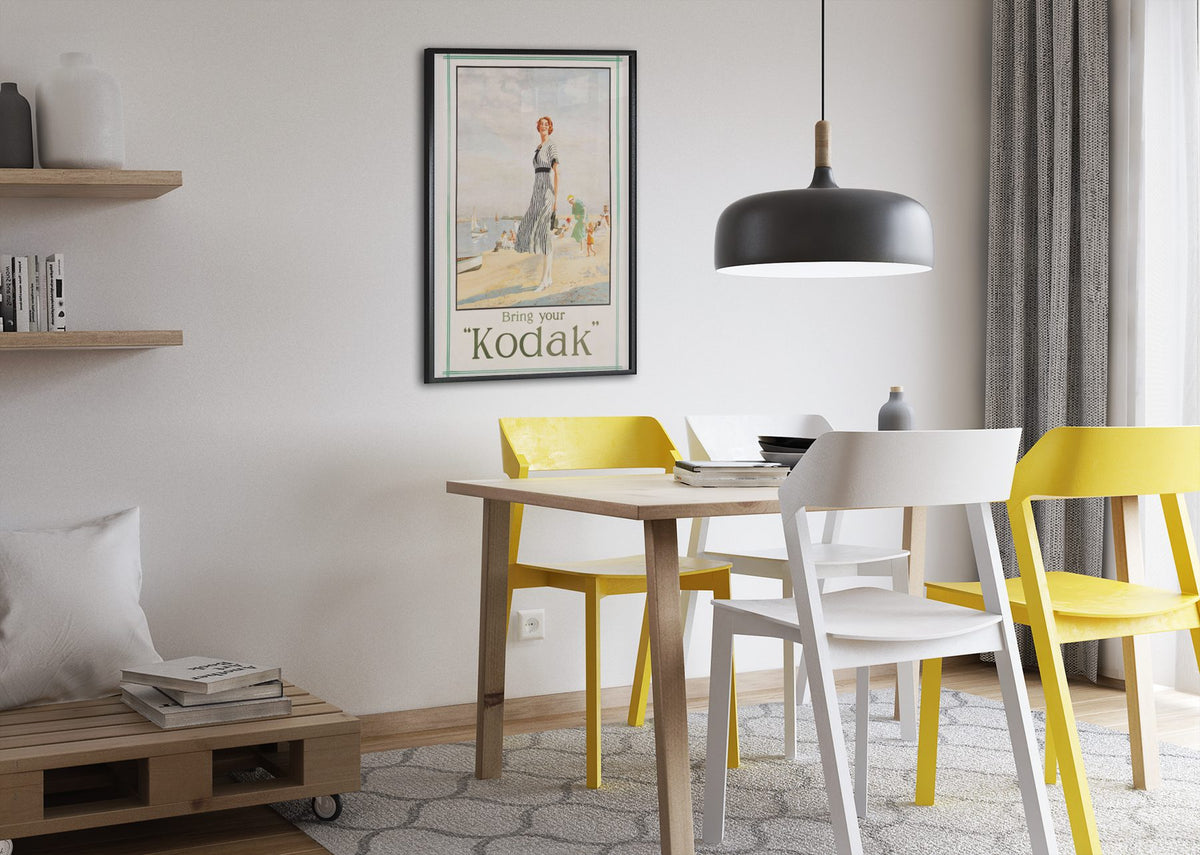 Bring Your Kodak 1925 poster framed above a dining table