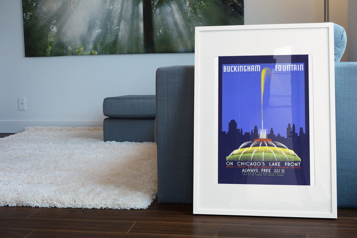 Buckingham Fountain Chicago poster leaning beside a blue sofa