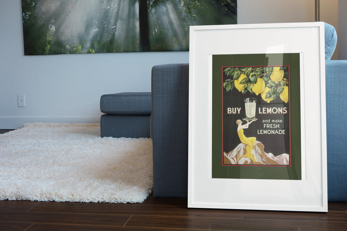 Buy Lemons 1920s lemonade poster in a white frame leaning beside a blue sofa