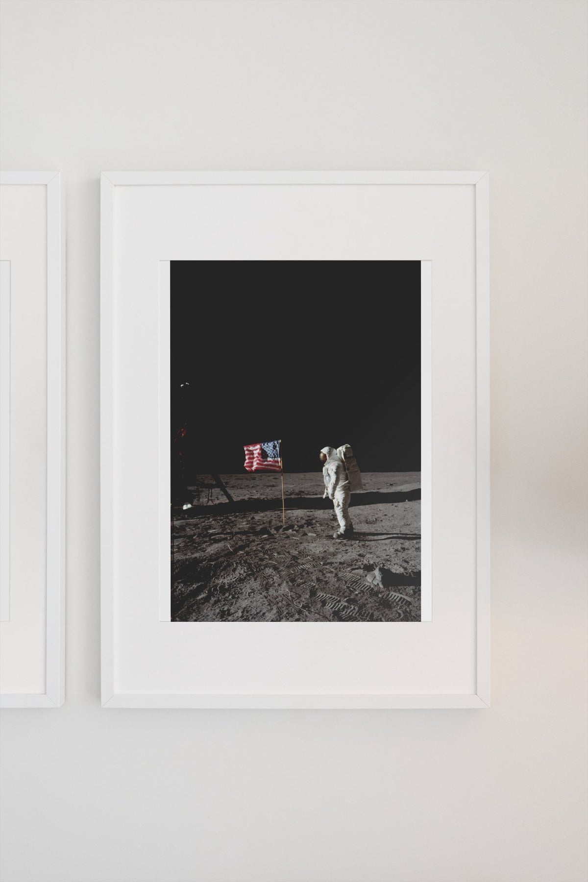 Buzz Aldrin with the US flag on the Moon poster in a white frame on a light wall