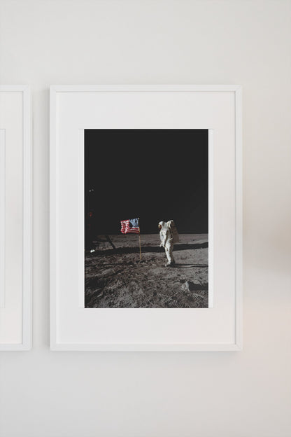 Buzz Aldrin with the US flag on the Moon poster in a white frame on a light wall