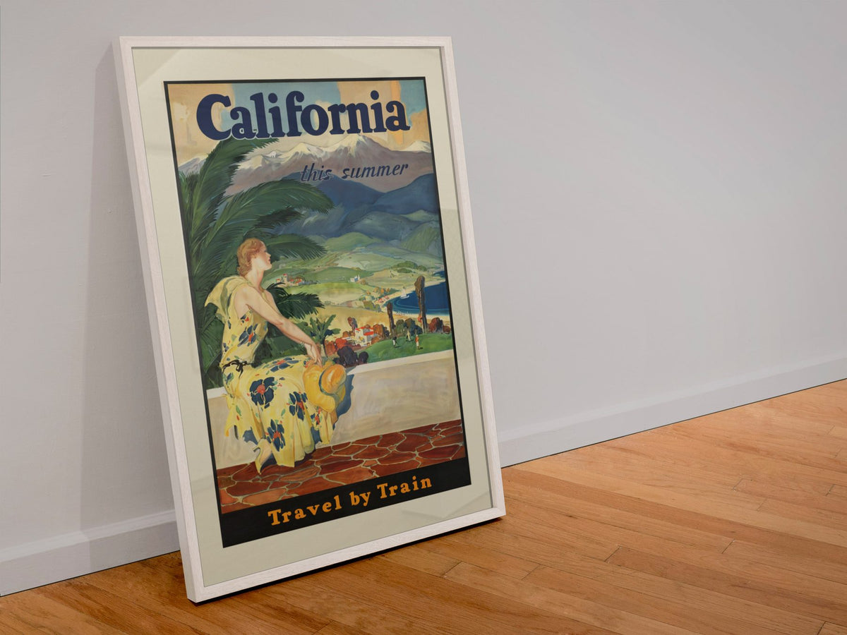 California This Summer — Travel by Train poster in a white frame leaning against a wall