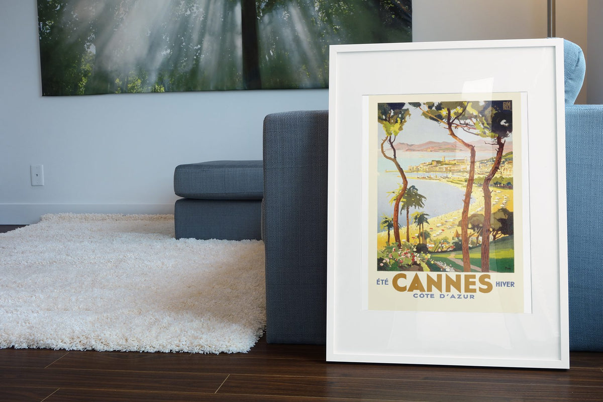 Cannes Cote d Azur poster leaning beside a blue sofa
