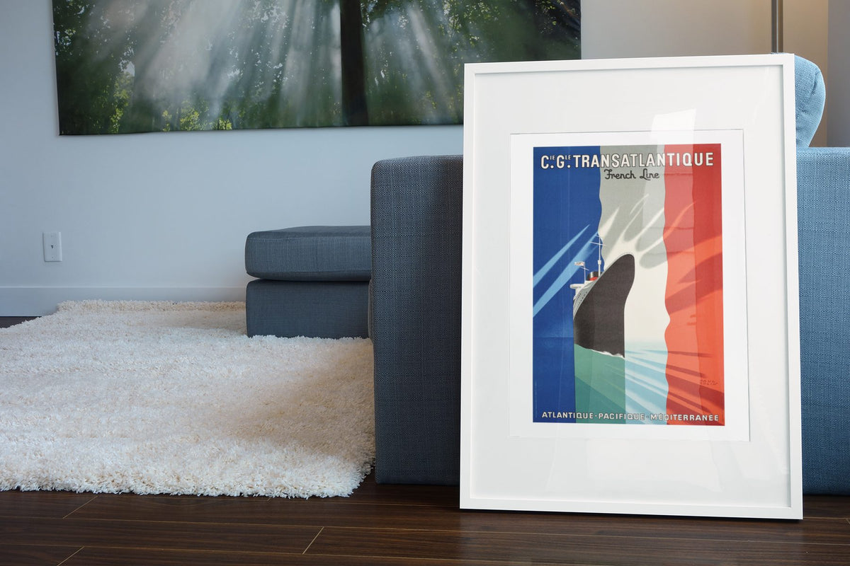 CGT Transatlantique French Line poster leaning beside a blue sofa