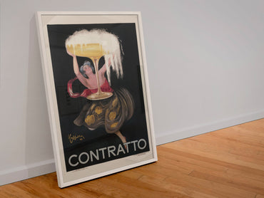 Contratto 1922 champagne by Cappiello poster in a white frame leaning against a wall
