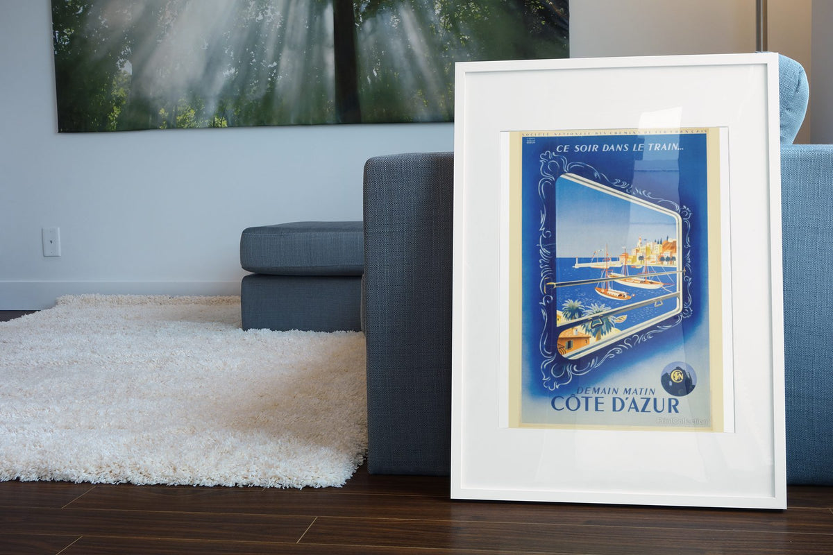 Cote d Azur by Train poster leaning beside a blue sofa