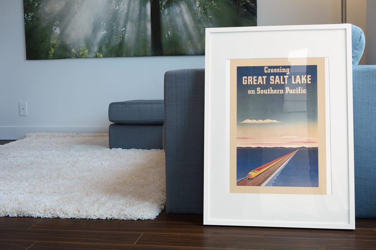 Crossing Great Salt Lake Southern Pacific poster leaning beside a blue sofa