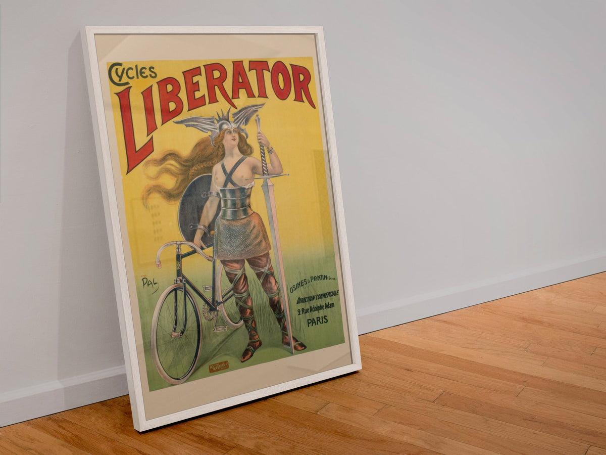 Cycles Liberator 1899 bicycle poster in a white frame leaning against a wall