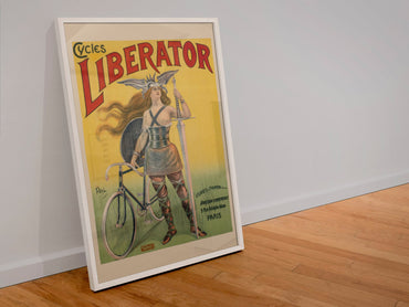 Cycles Liberator 1899 bicycle poster in a white frame leaning against a wall